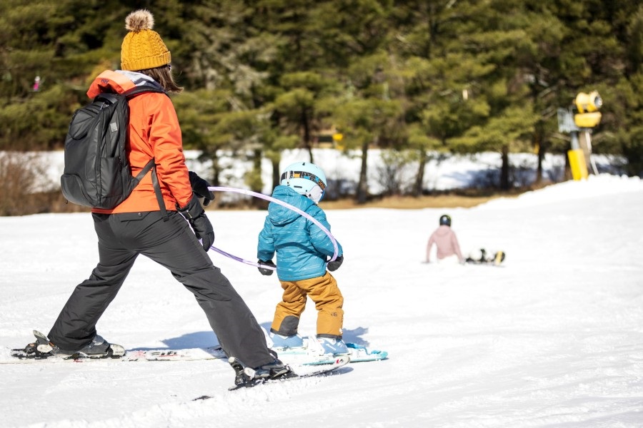 Mom and child skiing on Boyce Park slopes using a hula hoop to guide the child.